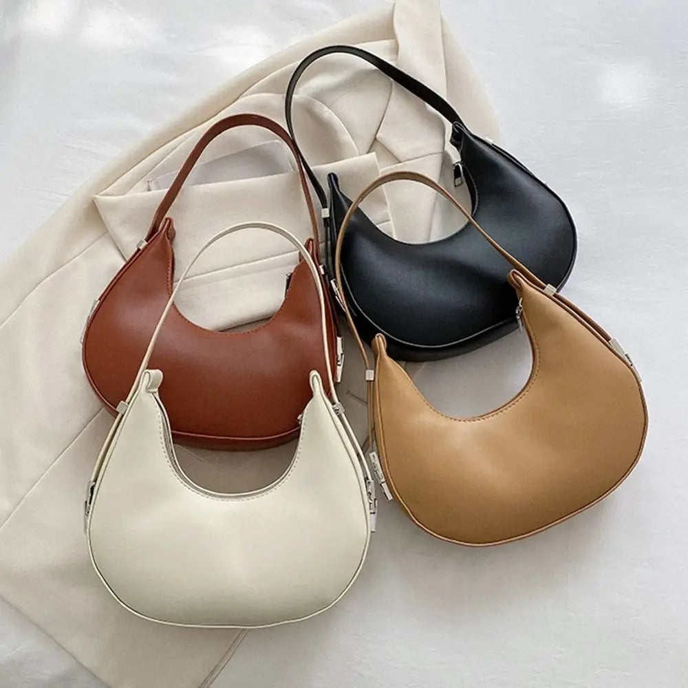 Four handbags in brown, black, beige, and white on a light fabric background